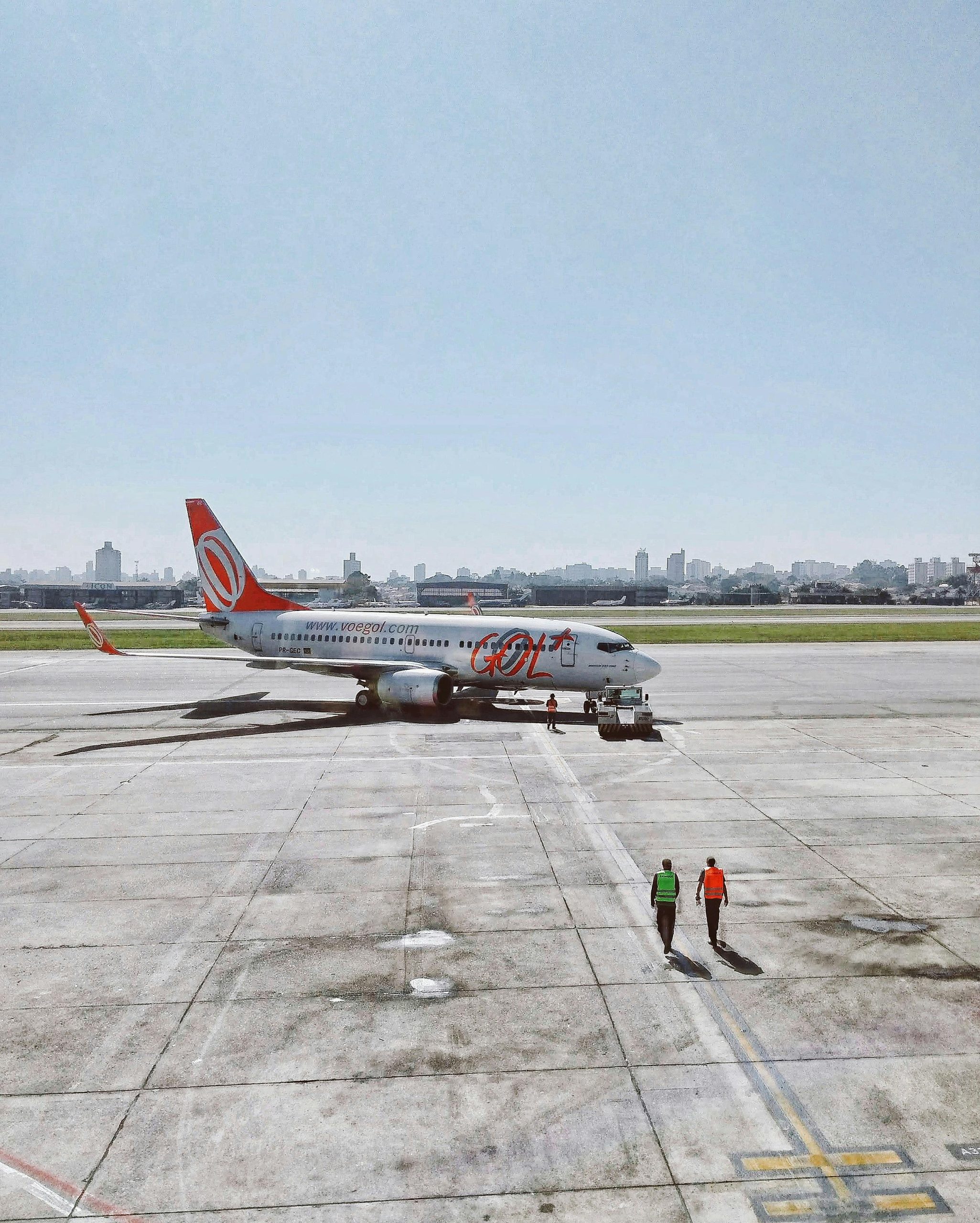 An airliner parked on the tarmac with two crew members approaching.