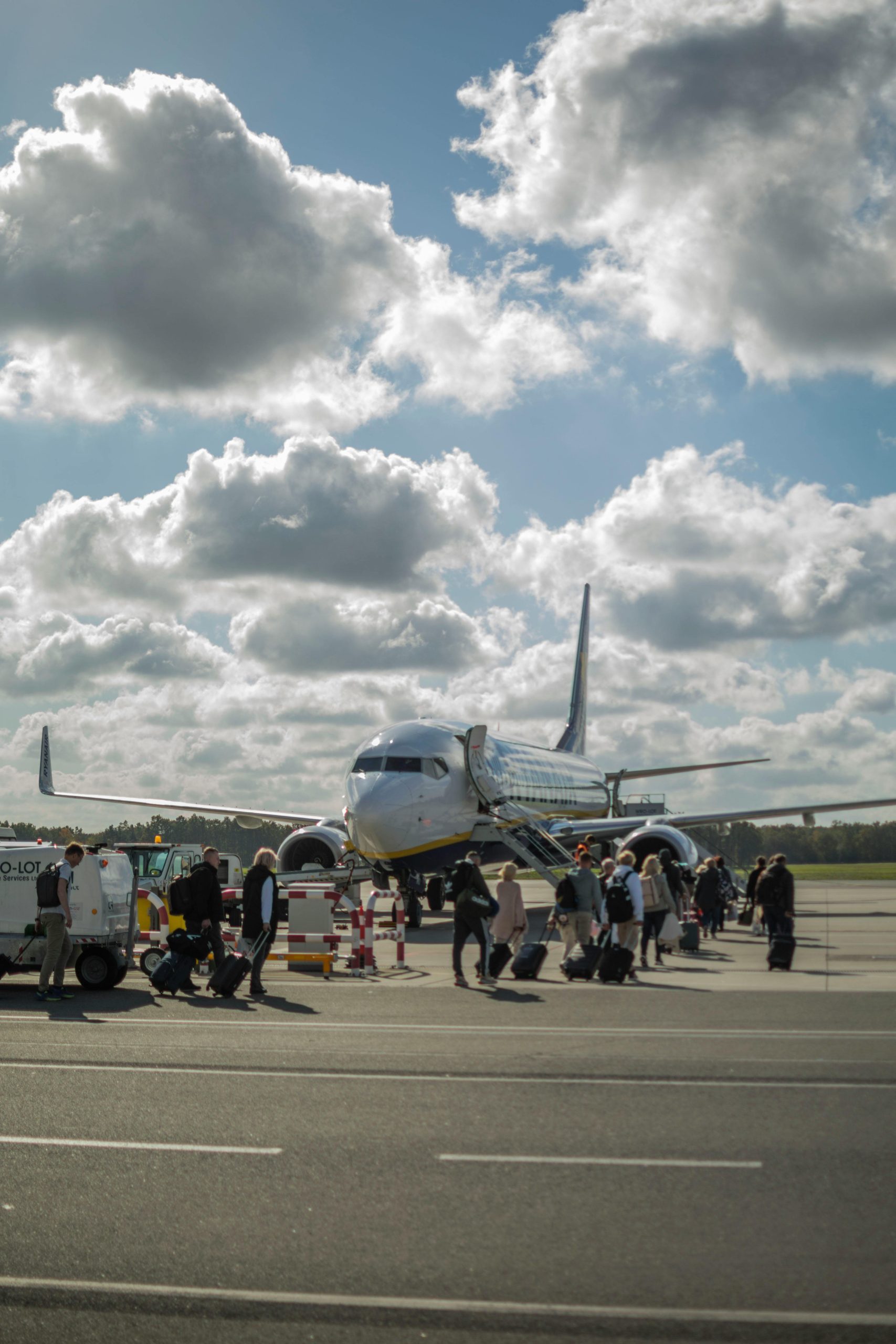 Travelers boarding a passenger airplane at Wrocław airport on a sunny day.